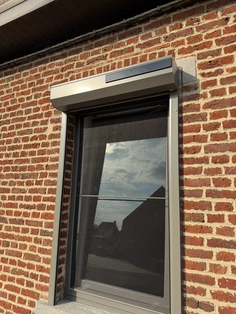 Volet roulant solaire à caisson pan coupé posé en applique sur brique
