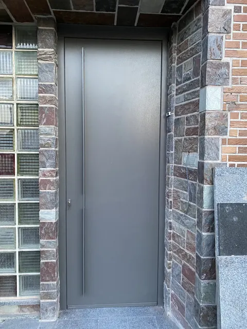 Porte d'entrée moderne grise à panneau plein, bâton de maréchal inox
